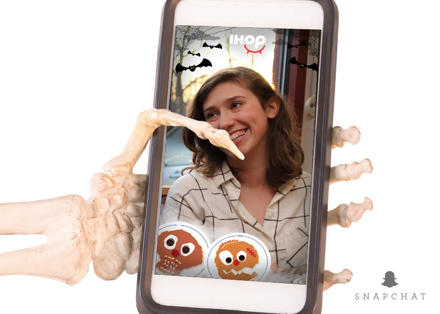 Snapchat filter on a phone: skeleton hands and scary-face pancakes around a smiling girl